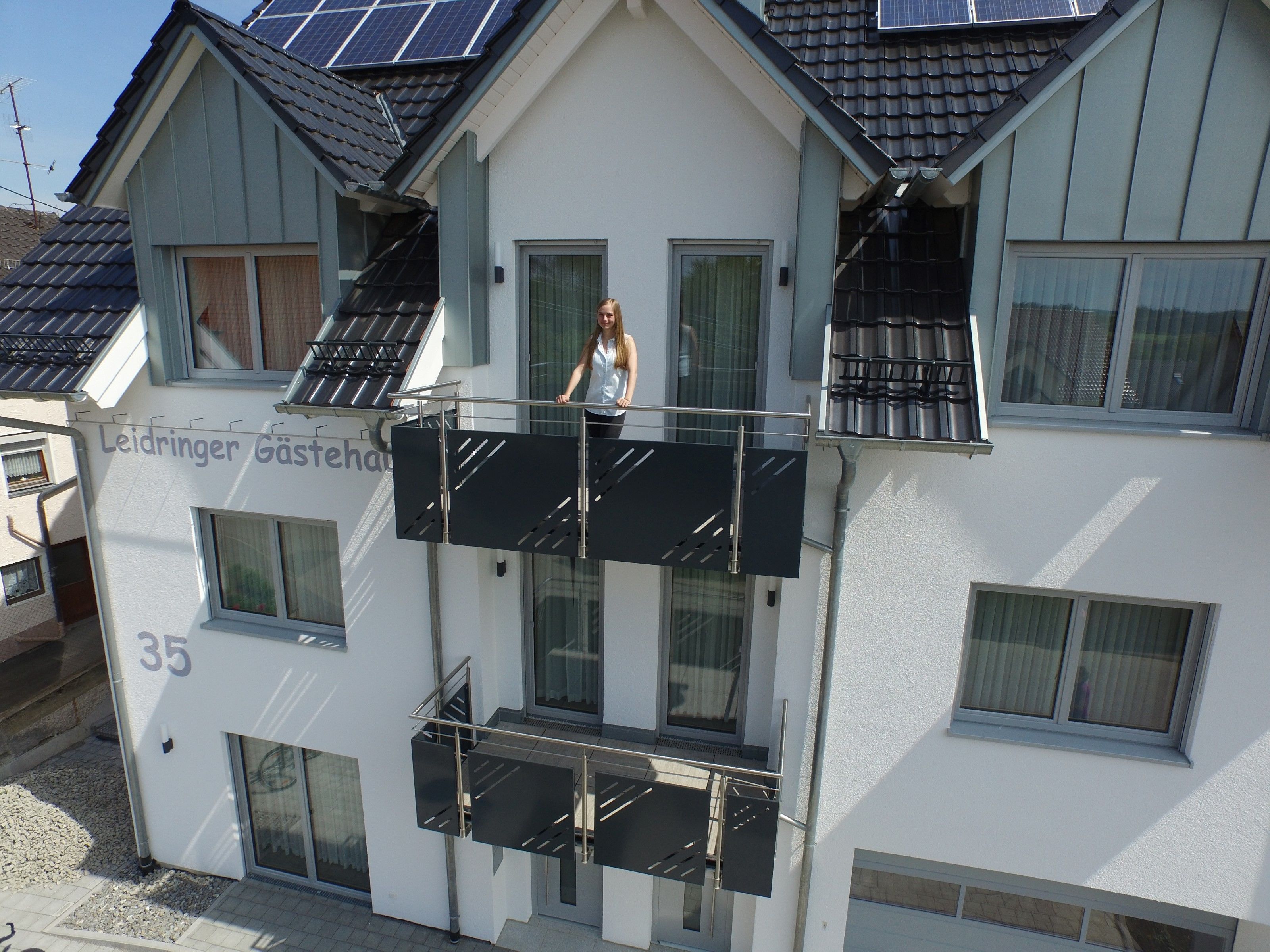 A two-story building with a balcony and solar panels on the roof.