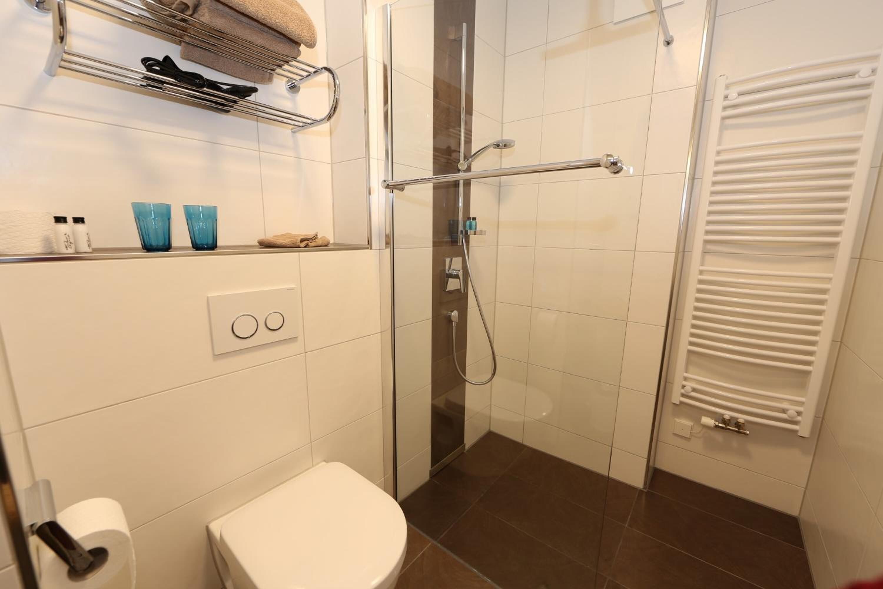 Ein modernes Badezimmer mit Duschkabine aus Glas, Toilette, Handtuchhalter und Handtuchwärmer.