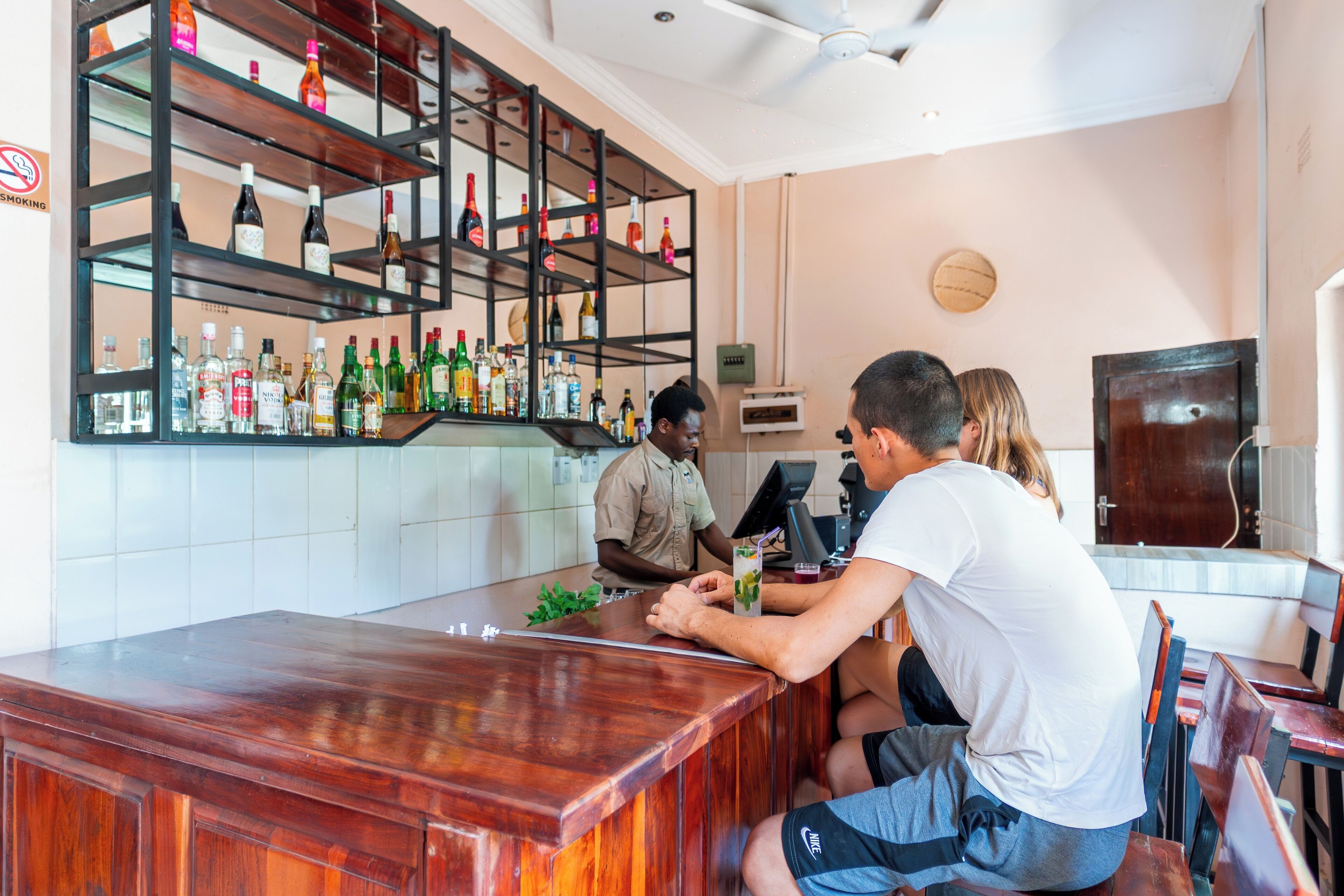 A bar area with a wooden counter and shelves stocked with bottles.