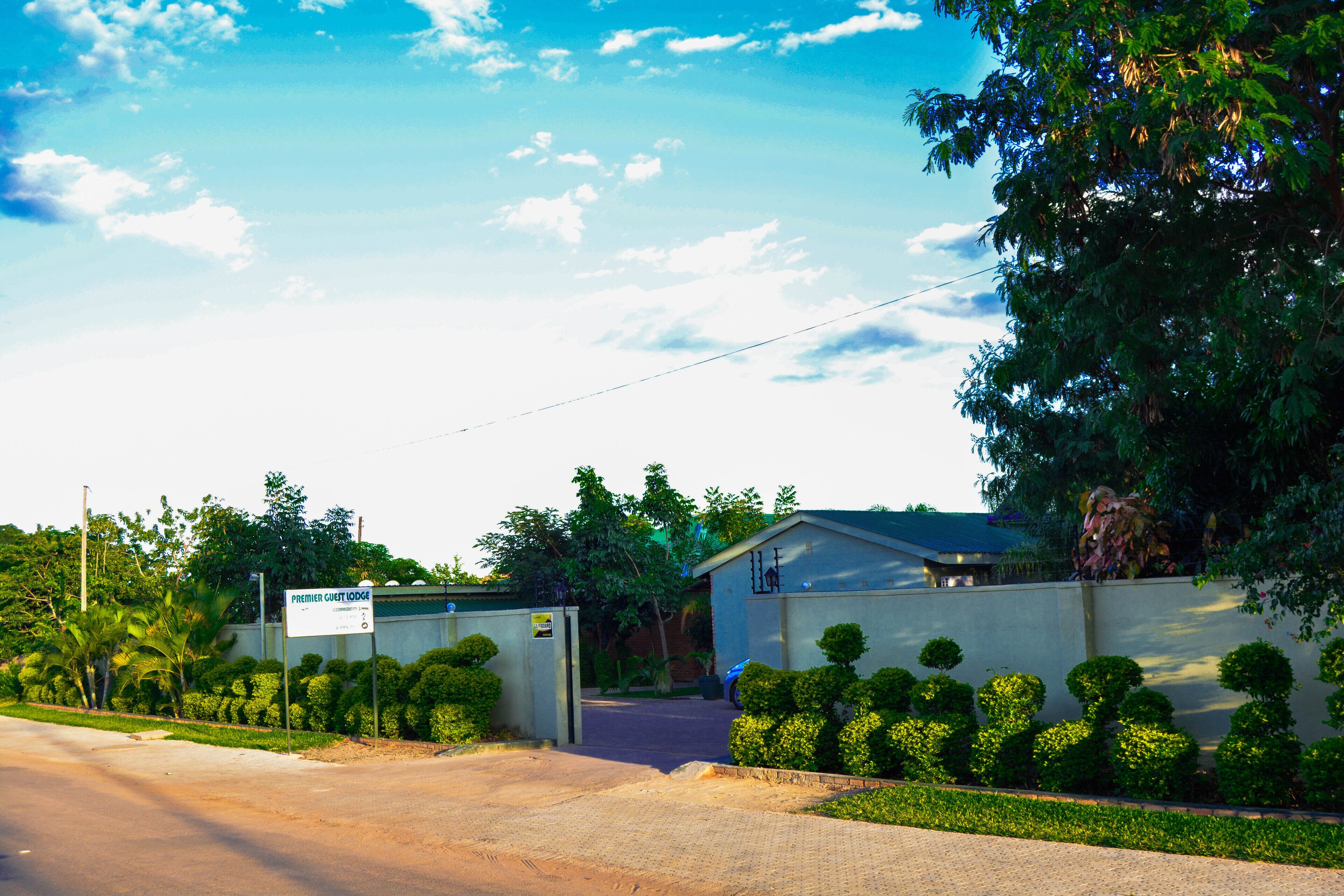 A gated entrance to a property with a sign reading "Premier Guest Lodge."