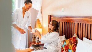 A hotel room with a bed, a bedside table, a lamp, and a canopy bed. - Premier Guest Lodge (Victoria Falls)