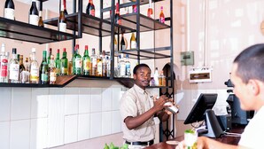 A bar area with shelves of various liquor bottles and a bar counter. - Premier Guest Lodge (Victoria Falls)