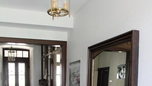 A hallway with a tiled floor, a wooden bench, a large mirror, and a door leading to another room. - Ancien Presbytère Albert Schweitzer (Gunsbach)