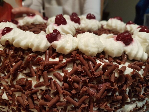 Un postre con crema batida, virutas de chocolate y cerezas.