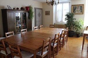 Un comedor con mesa y sillas de madera, una estantería y una araña.
