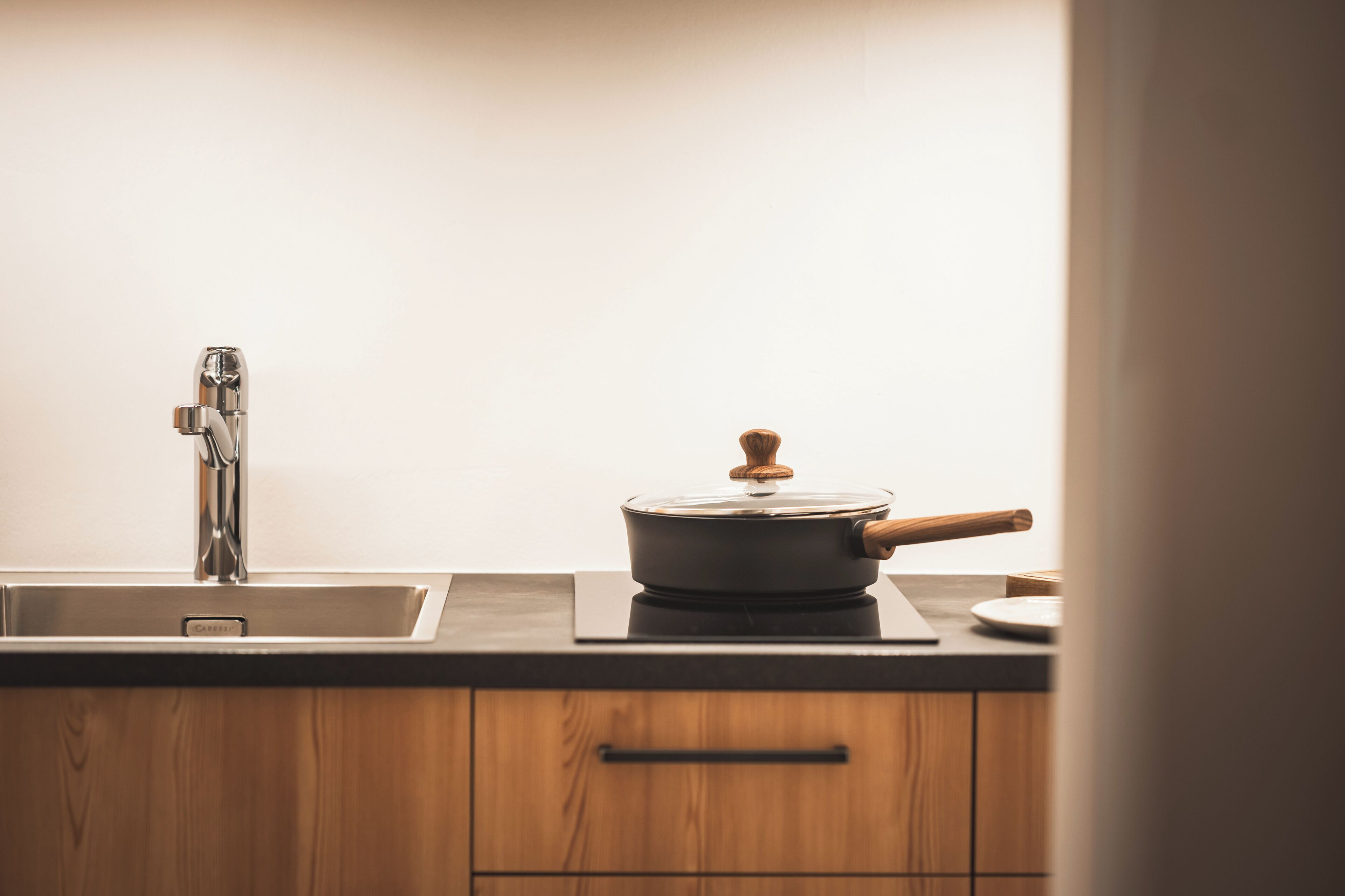 Une cuisine équipée d’un évier en acier inoxydable, d’une cuisinière et de meubles de rangement en bois.