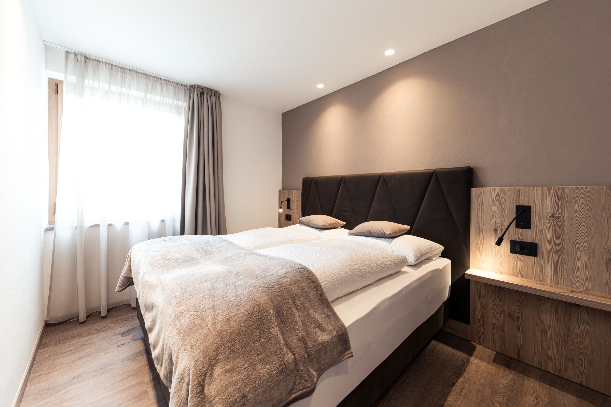 Una camera da letto moderna con un letto grande, una testiera in legno e un comodino con una lampada.