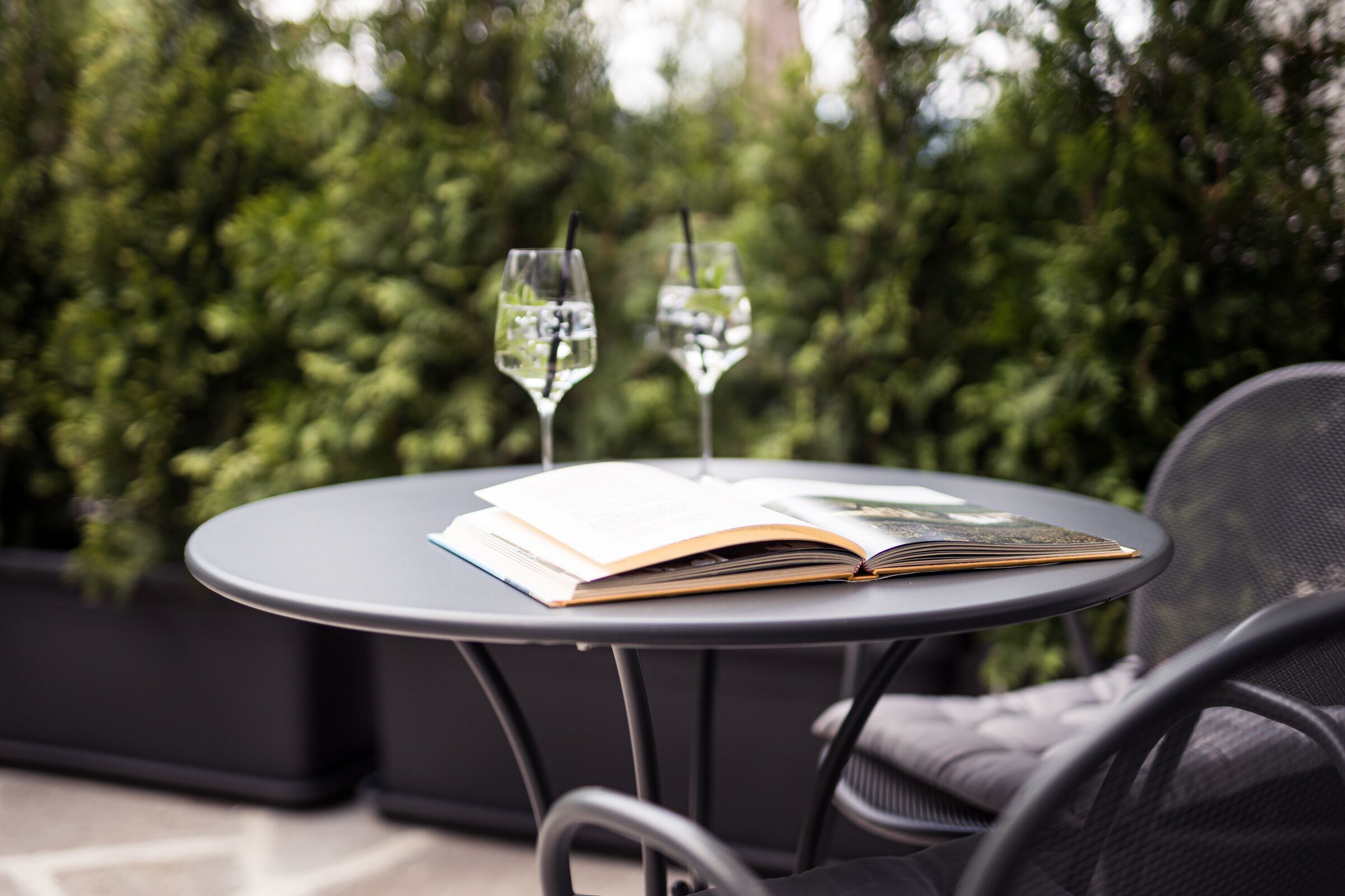 A round table with two wine glasses and an open book.