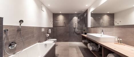 A modern bathroom with a bathtub, a sink, and a shower area.