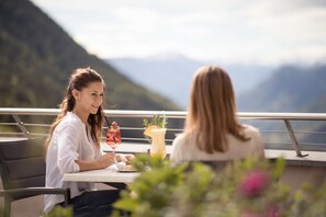 Two people seated at an outdoor table with a mountain view in the background. - Hotel Berghang (Cornedo All'isarco)