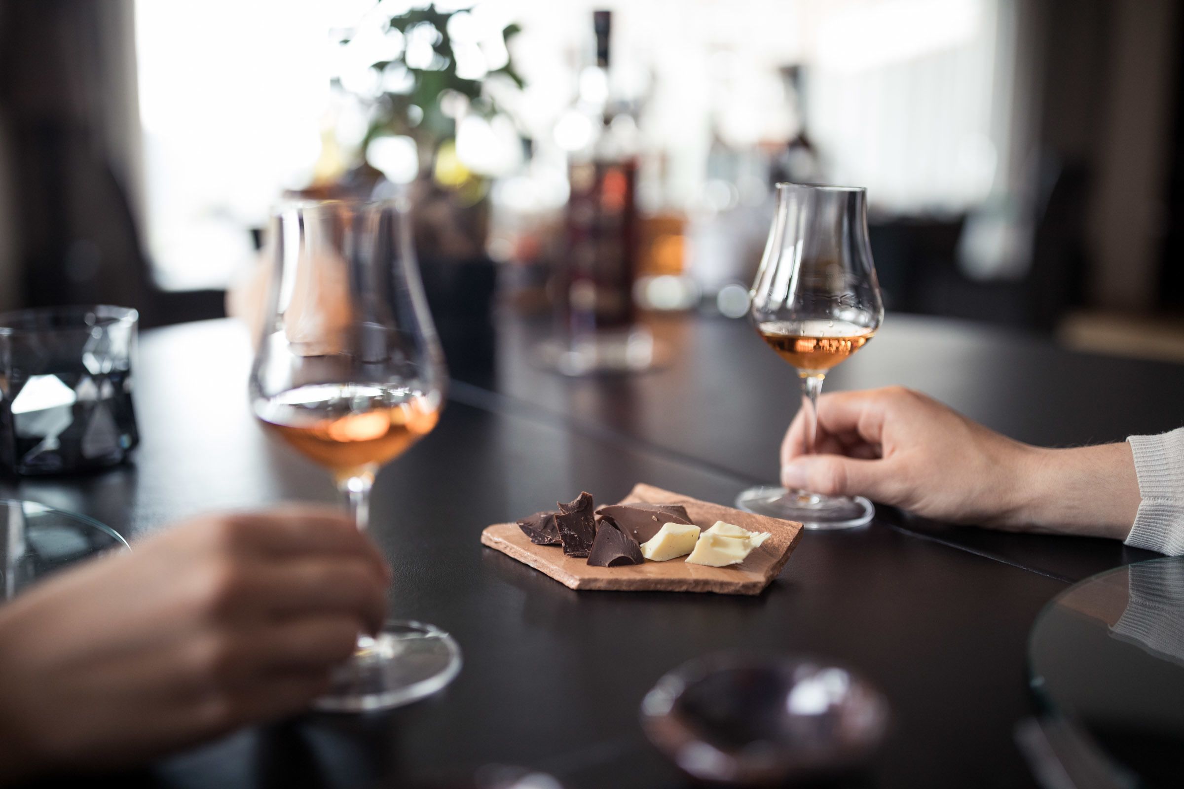 Una mesa con dos copas de vino rosado, un postre de chocolate y una botella al fondo.