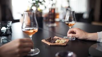 Una mesa con dos copas de vino rosado, un postre de chocolate y una botella al fondo.