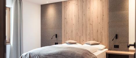 A modern bedroom with a large bed, wooden panel wall, and built-in nightstands.