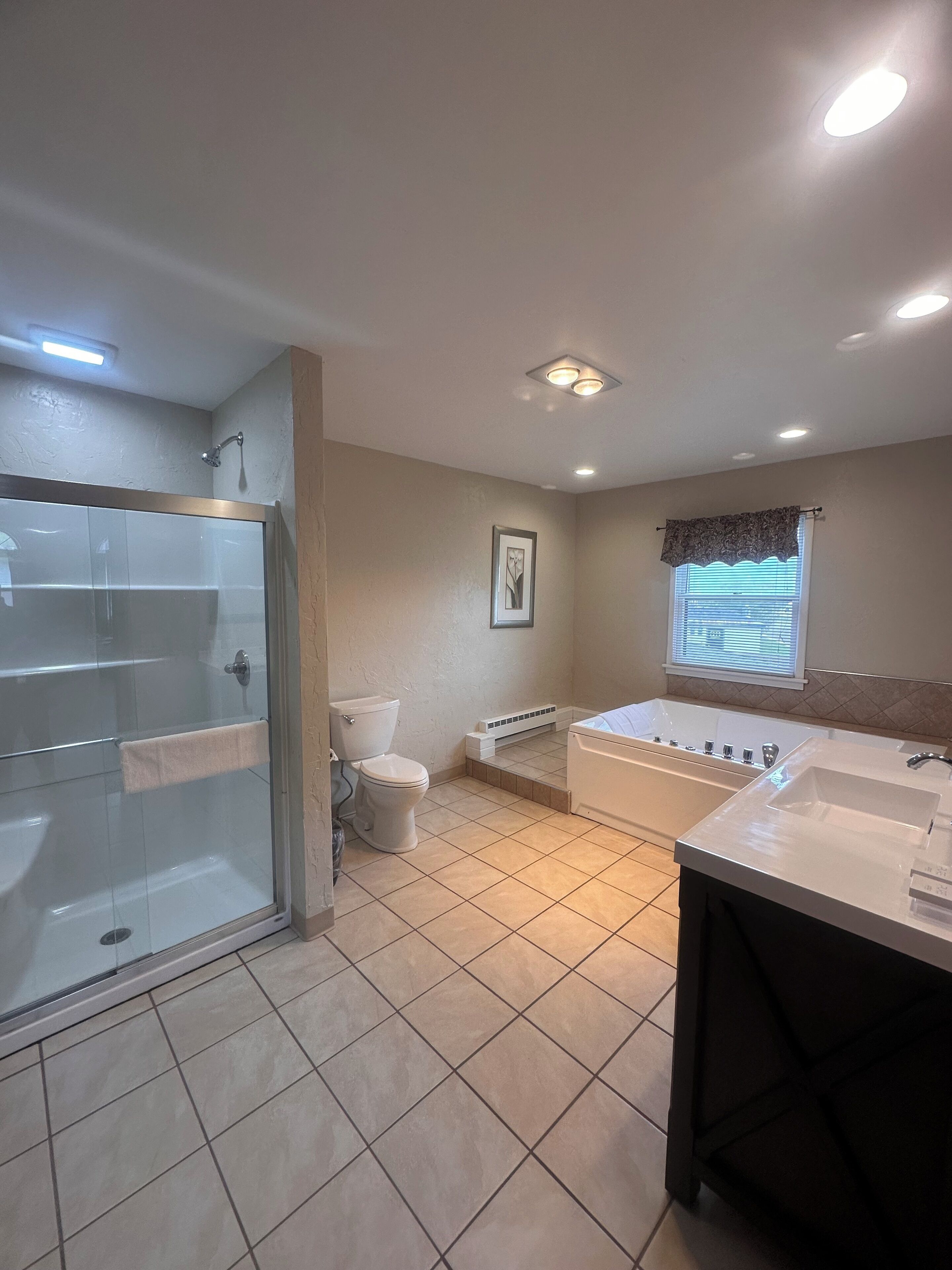 A bathroom with a glass-enclosed shower, a toilet, a bathtub, and a sink.