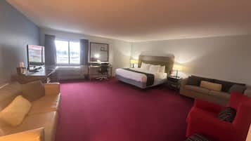 Habitación de hotel con cama, escritorio, silla, sofá y televisor.