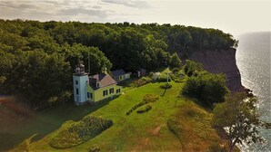 A coastal property with a lighthouse-style building, surrounded by lush greenery and a cliff overlooking the sea. - Pictured Rocks Inn & Suites (Munising)