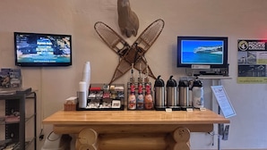 A reception desk with a mounted deer head, two TVs, and a wooden counter with various items. - Pictured Rocks Inn & Suites (Munising)
