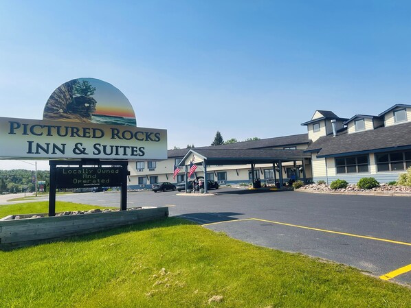 A hotel sign with a scenic view, a covered parking area, and a building with multiple windows.