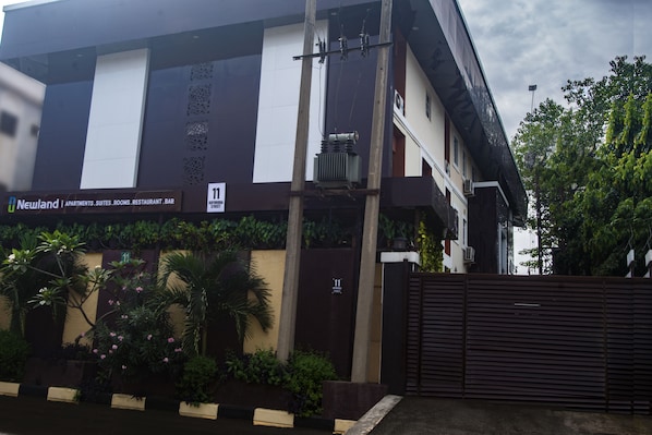 Un edificio con cartel anunciando Newland Apartments, Suites, Habitaciones, Restaurante y Bar.