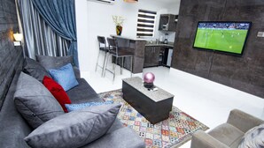 Ein modernes Wohnzimmer mit grauem Sofa, einem Couchtisch und einem an der Wand montierten Fernseher.