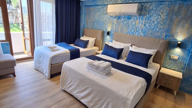 A hotel room with two beds, a large window, and an air conditioning unit on the wall. - Dilmac Hotel (Gallipoli)