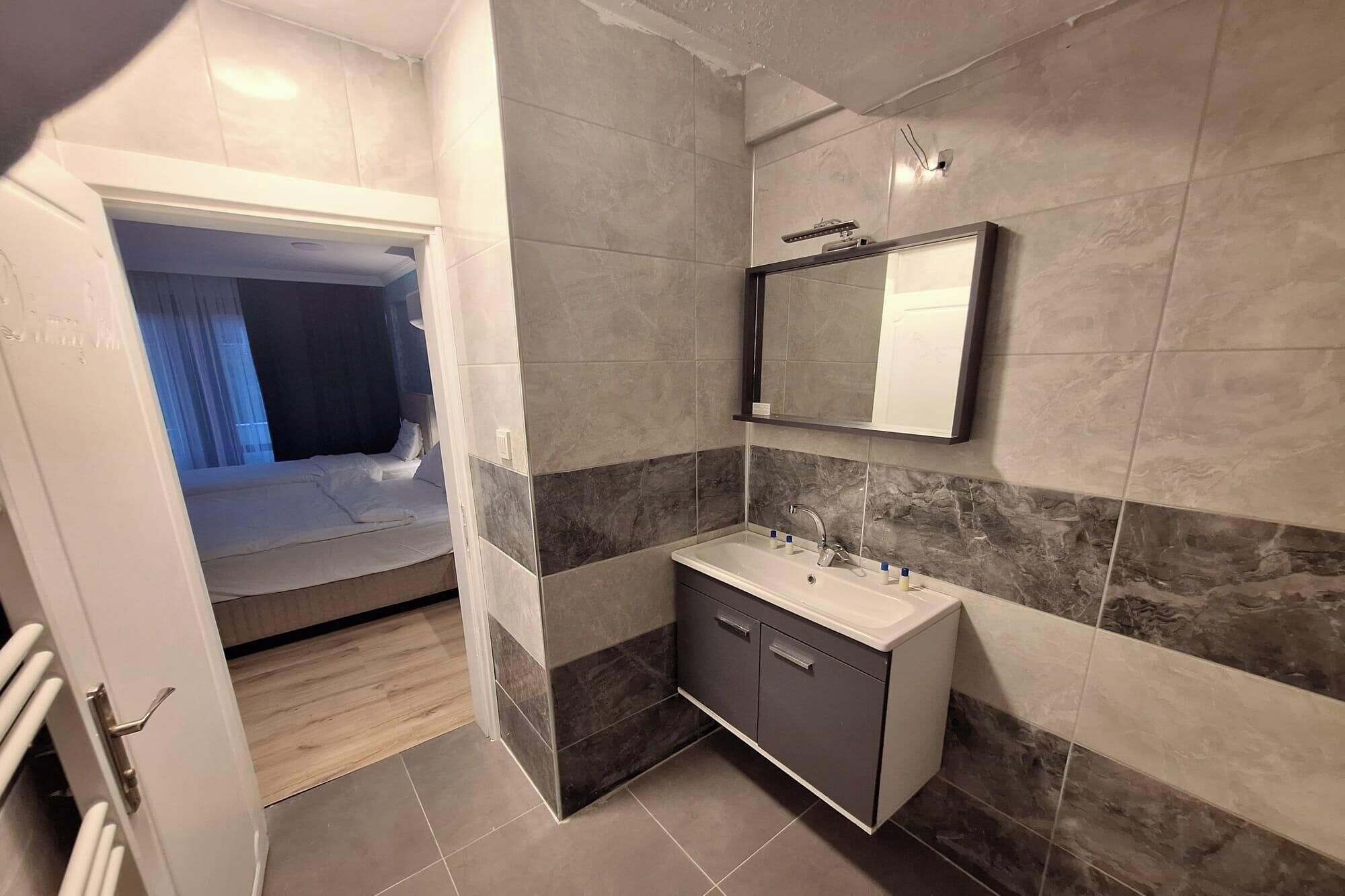 Un baño moderno con un espejo grande, un lavabo y una ducha.