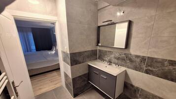 Un baño moderno con un espejo grande, un lavabo y una ducha.