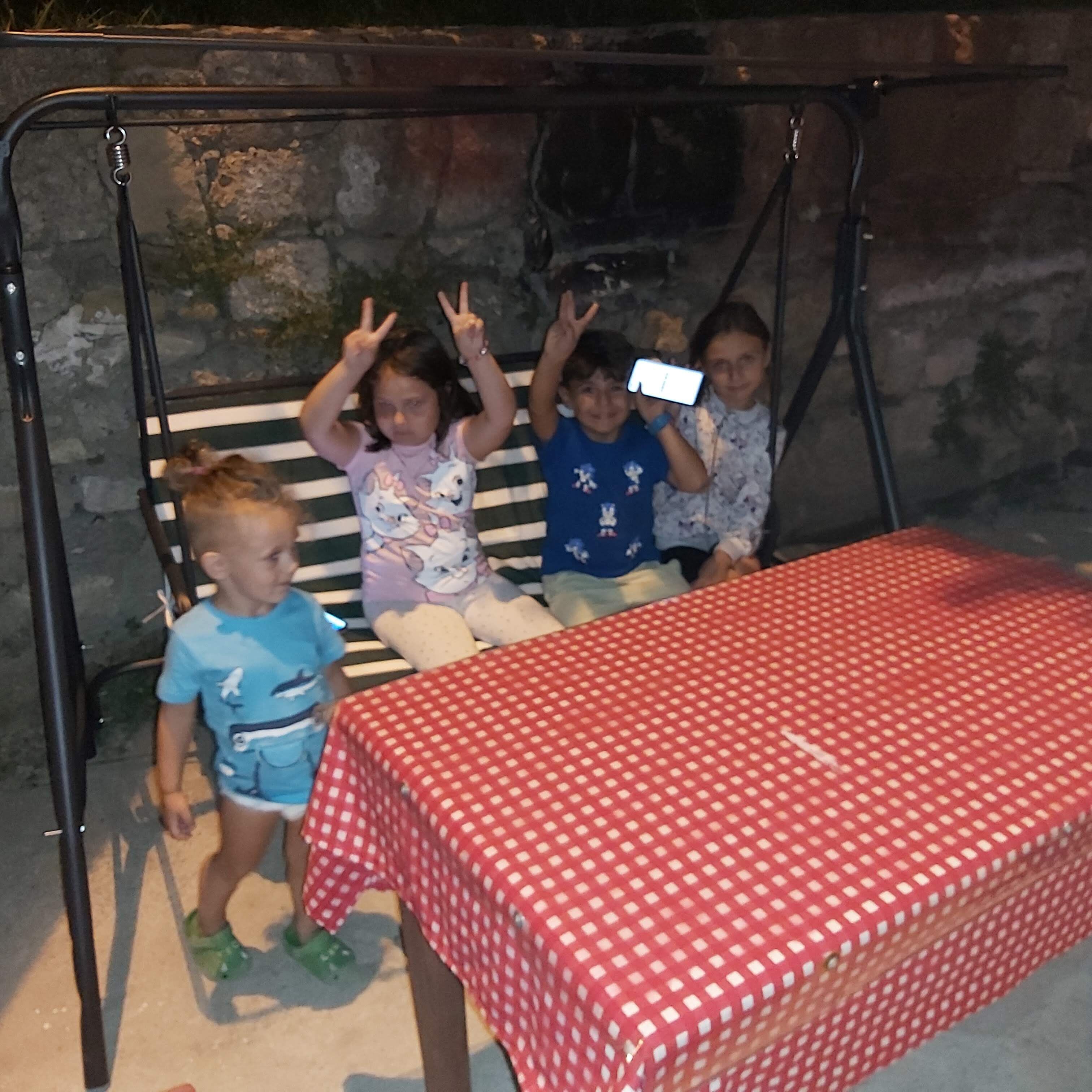 A swing set with a metal frame and a red checkered tablecloth.