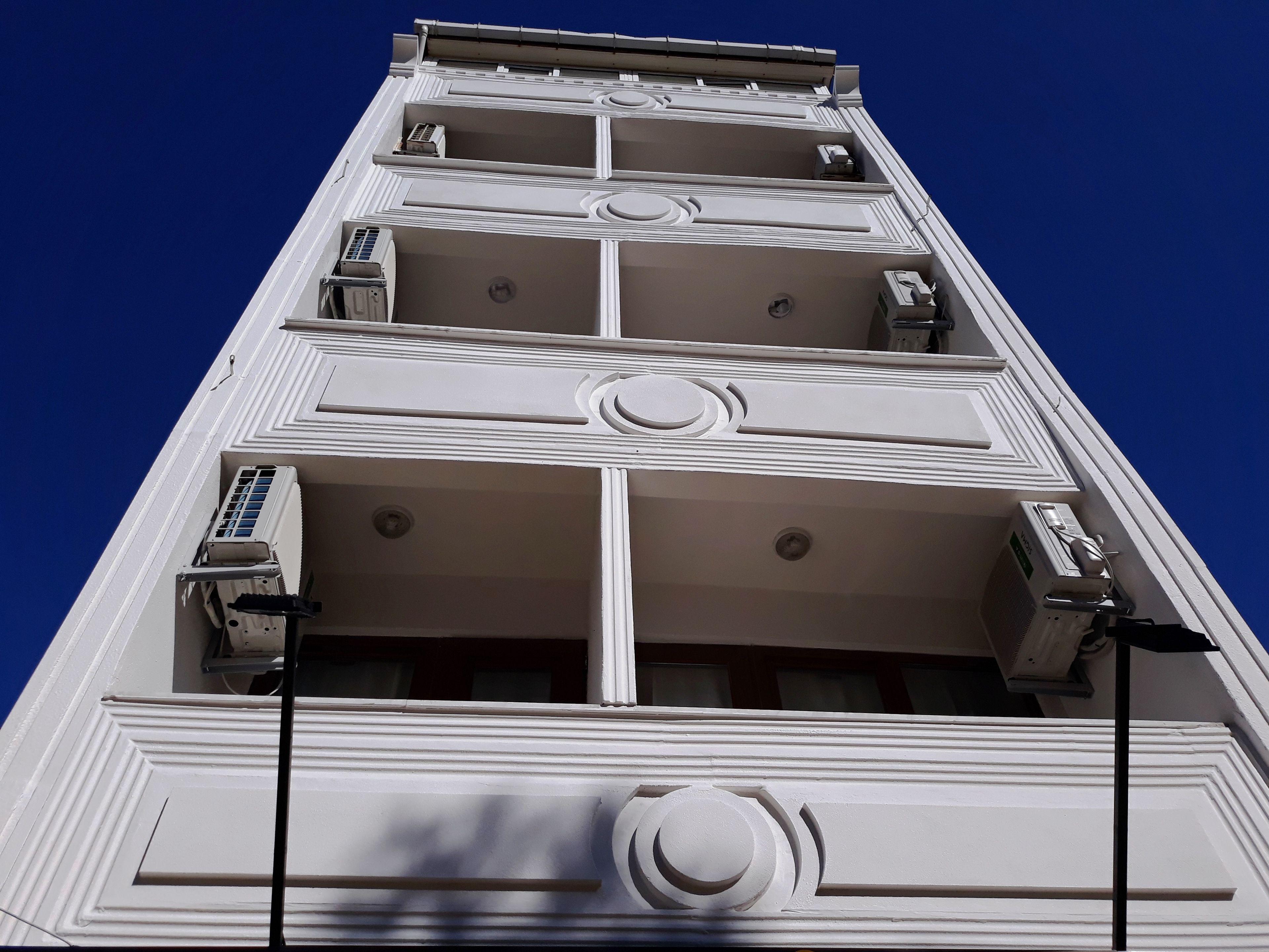 Un edificio alto con varios pisos, cada uno con balcón y unidades de aire acondicionado.