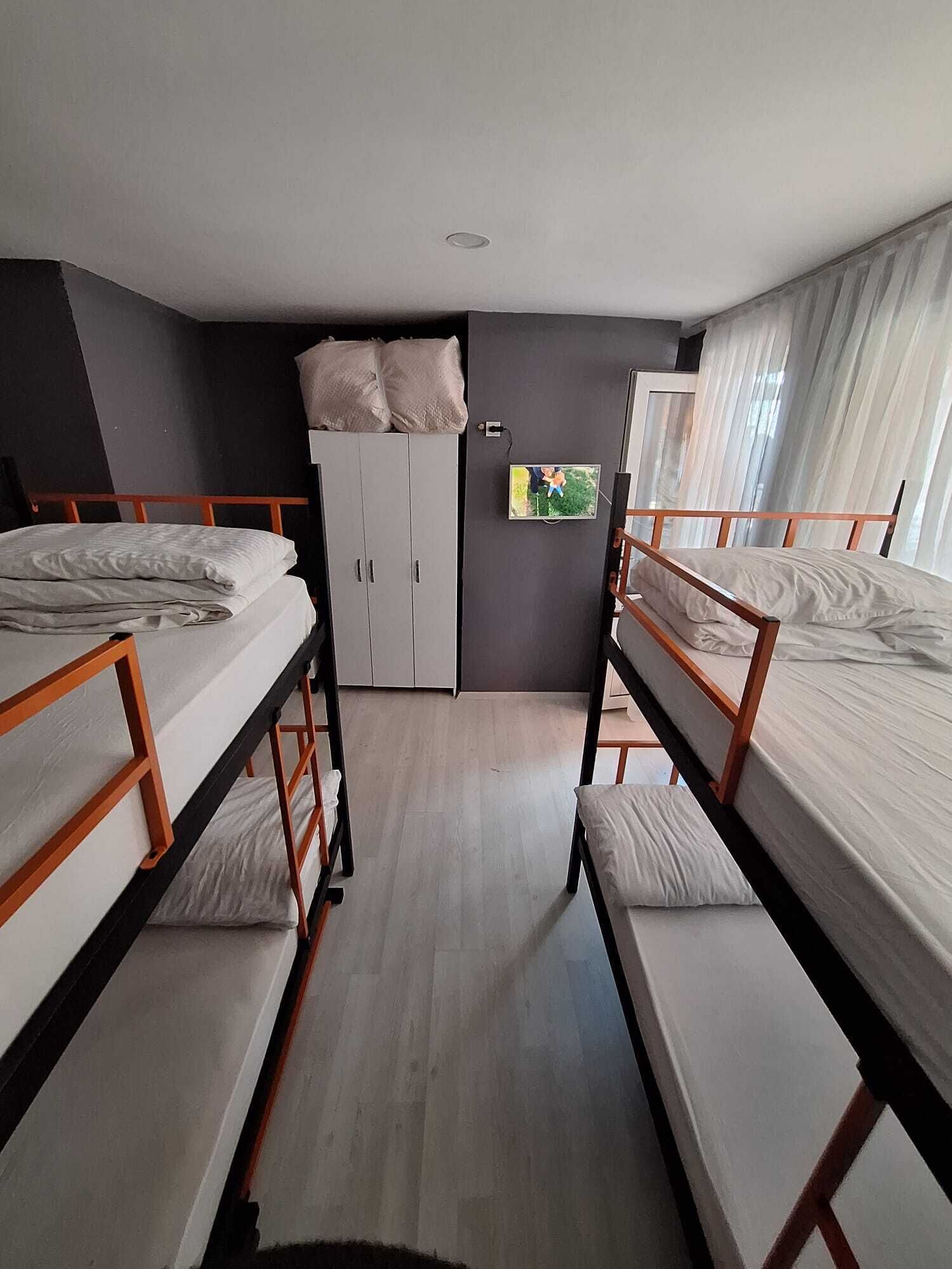 A dorm-style room with bunk beds, a wardrobe, and a television.