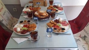 A table set with various dishes, including bread, eggs, and olives, in a room with patterned curtains. - Dilmac Hotel (Gallipoli)