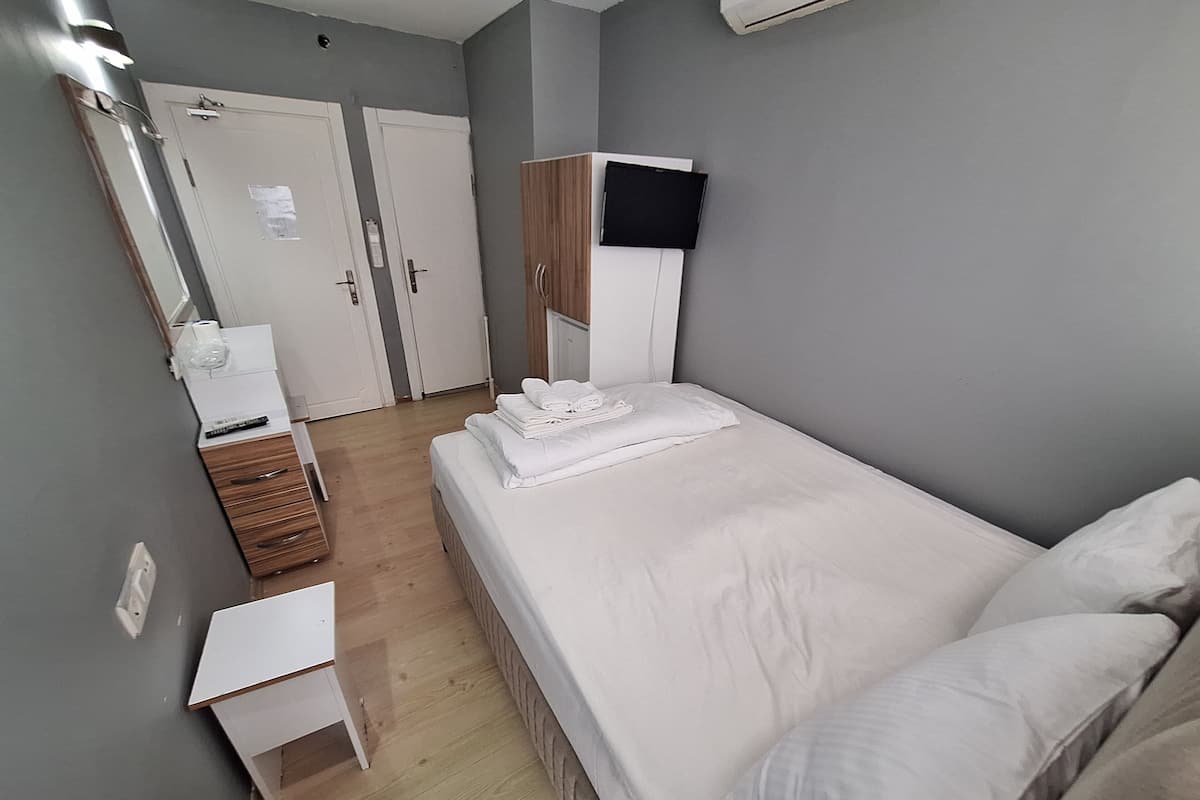 A bedroom with a bed, a bedside table, a wardrobe, and a mirror.