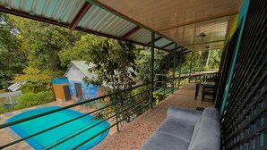 Varanda com piscina, um banco acolchoado e vista para uma casa com um mural.