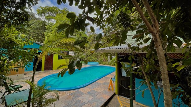 Piscina rodeada por vegetação exuberante e edifícios coloridos.