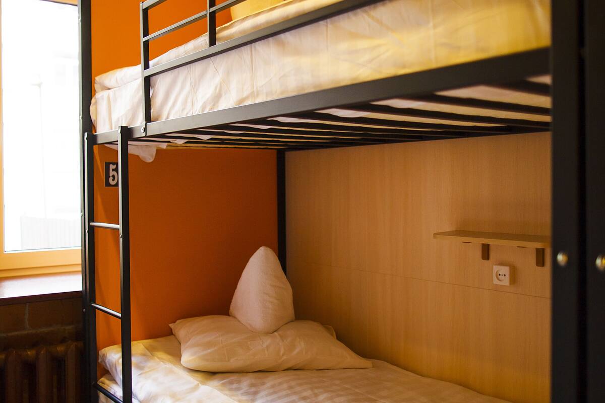 A bunk bed room with a window, wooden walls, and a number on the wall.