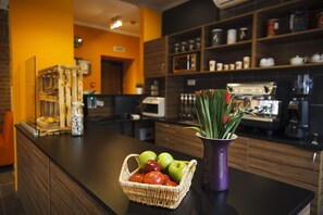 A kitchen with a fruit basket and a vase of flowers on the counter. - Portal Hostel and Hotel (Moscow)