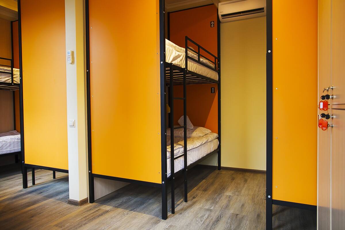 A dormitory room with bunk beds, a door with a number, and a fire extinguisher.