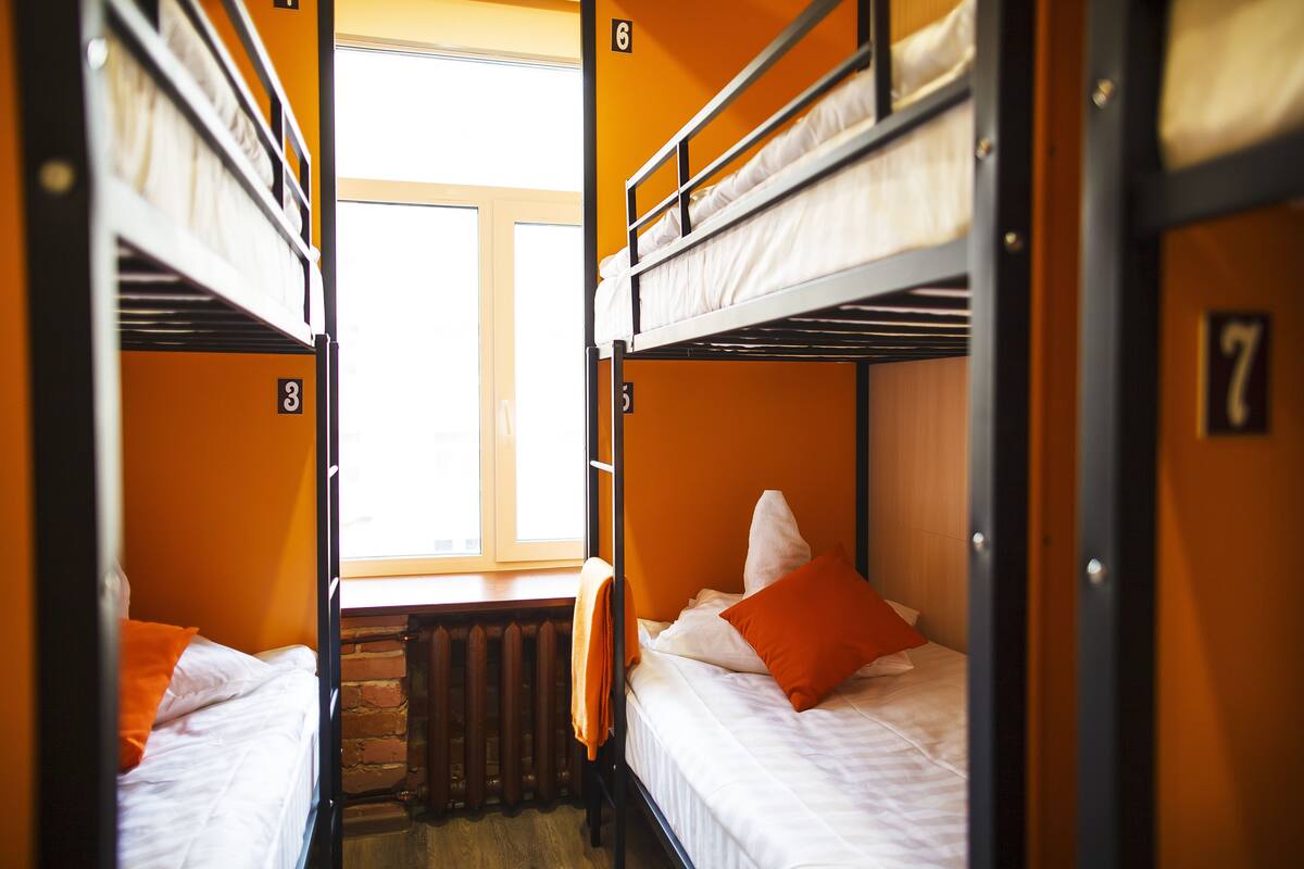 A dormitory room with bunk beds, numbered room 6, and a window providing natural light.