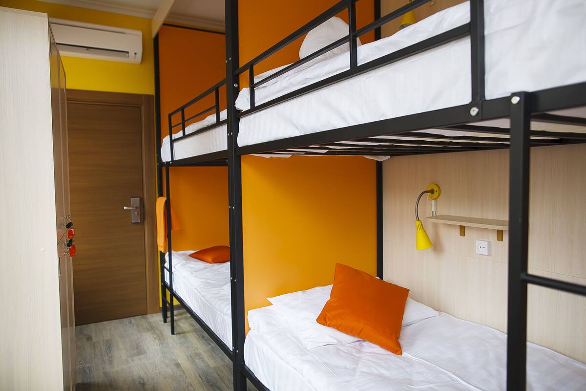 A bunk bed room with a wooden door, a yellow wall, and a bedside lamp.