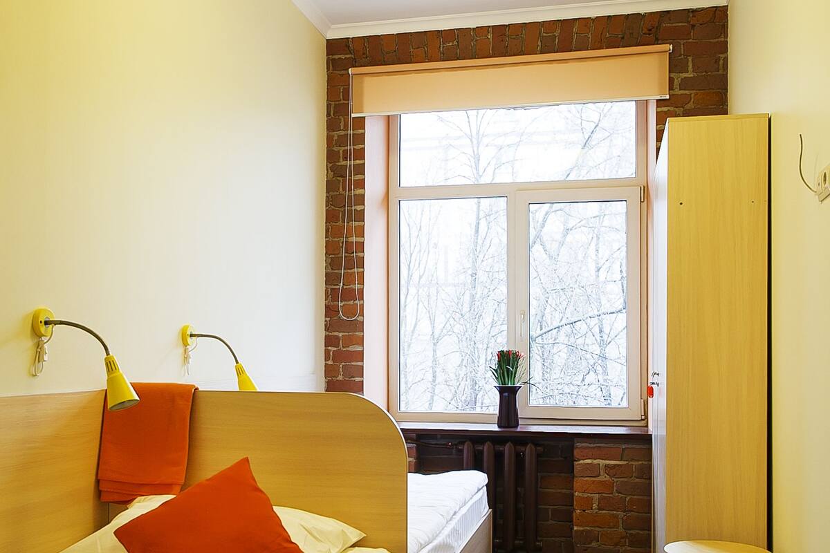 A compact bedroom with a bed, a small table, and a window.