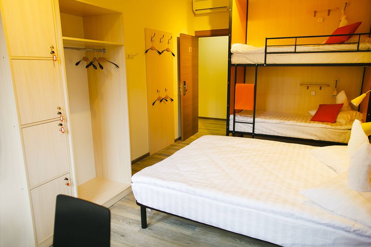 A dormitory room with bunk beds, a wardrobe, and a desk.