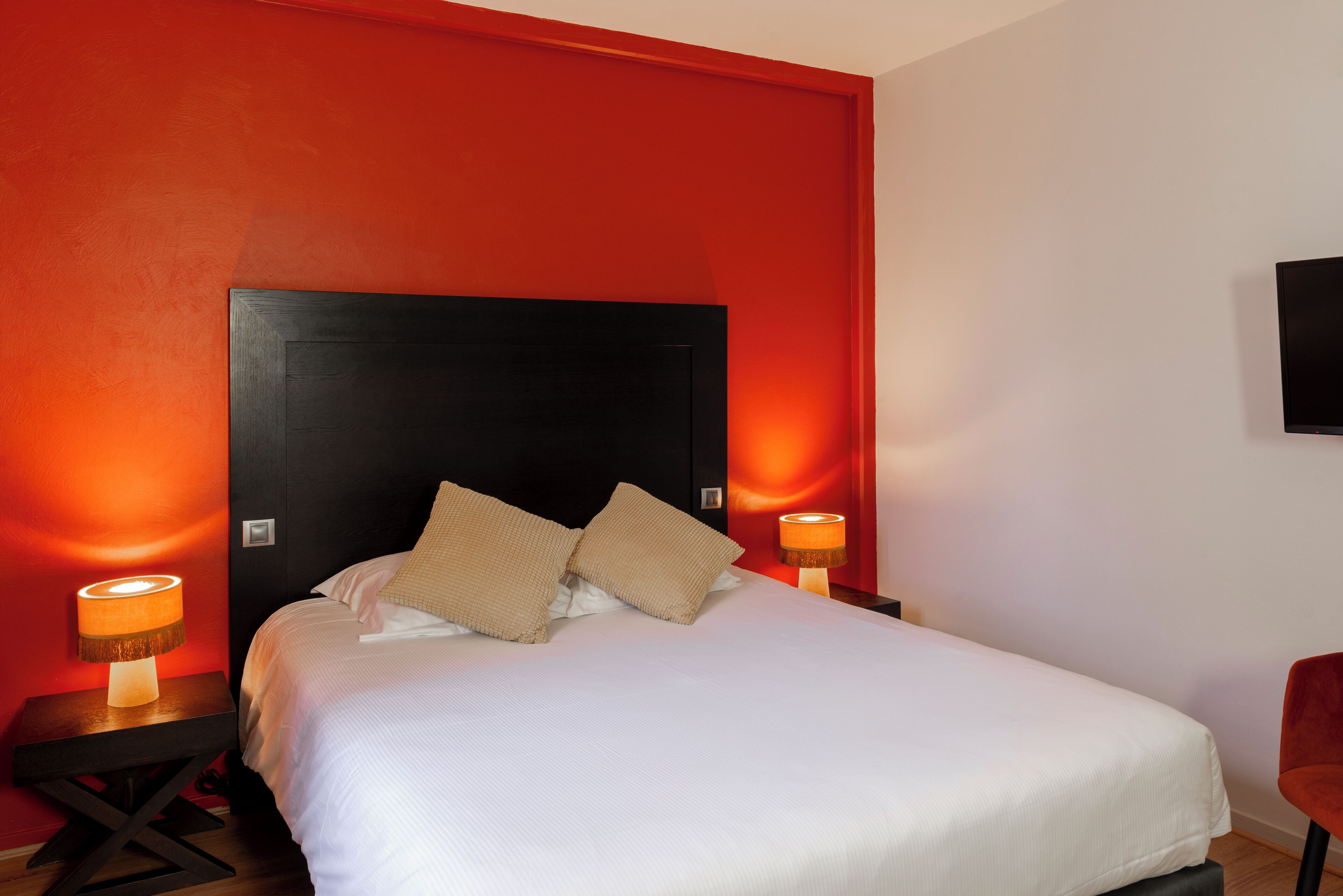 A hotel room with a large bed, two bedside tables, and a TV mounted on the wall.