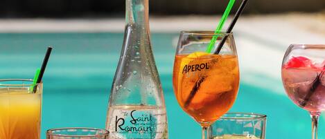 Variedad de bebidas sobre una mesa cerca de una piscina.