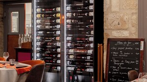A restaurant interior with a wine rack, tables with orange tablecloths, and a chalkboard menu. -  Logis Hotel-Restaurant Saint Romain (Anse)