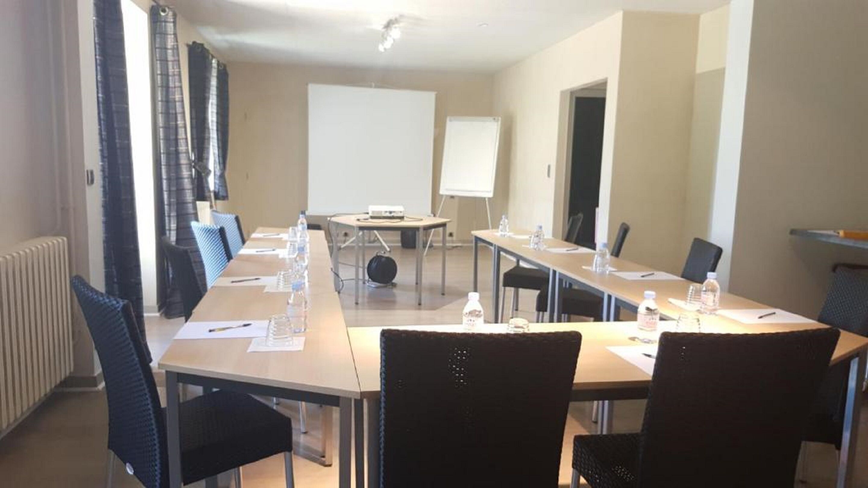 A conference room with a long table, chairs, a projector, and a whiteboard.