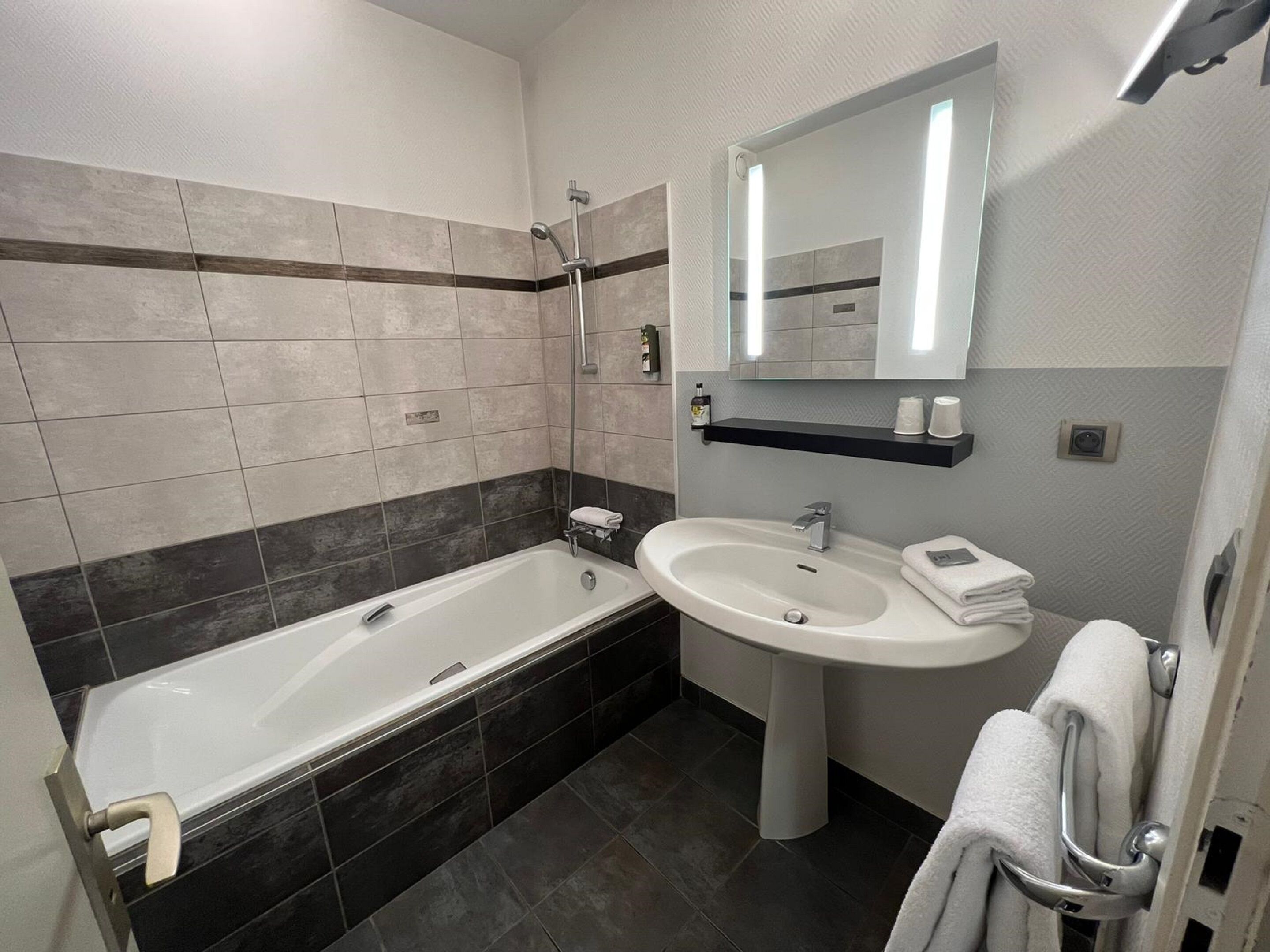 Un baño moderno con bañera, lavabo y espejo.