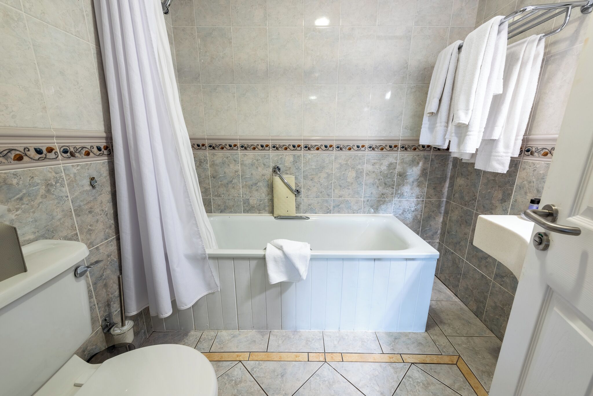 Un baño con bañera, inodoro y cortina de ducha.