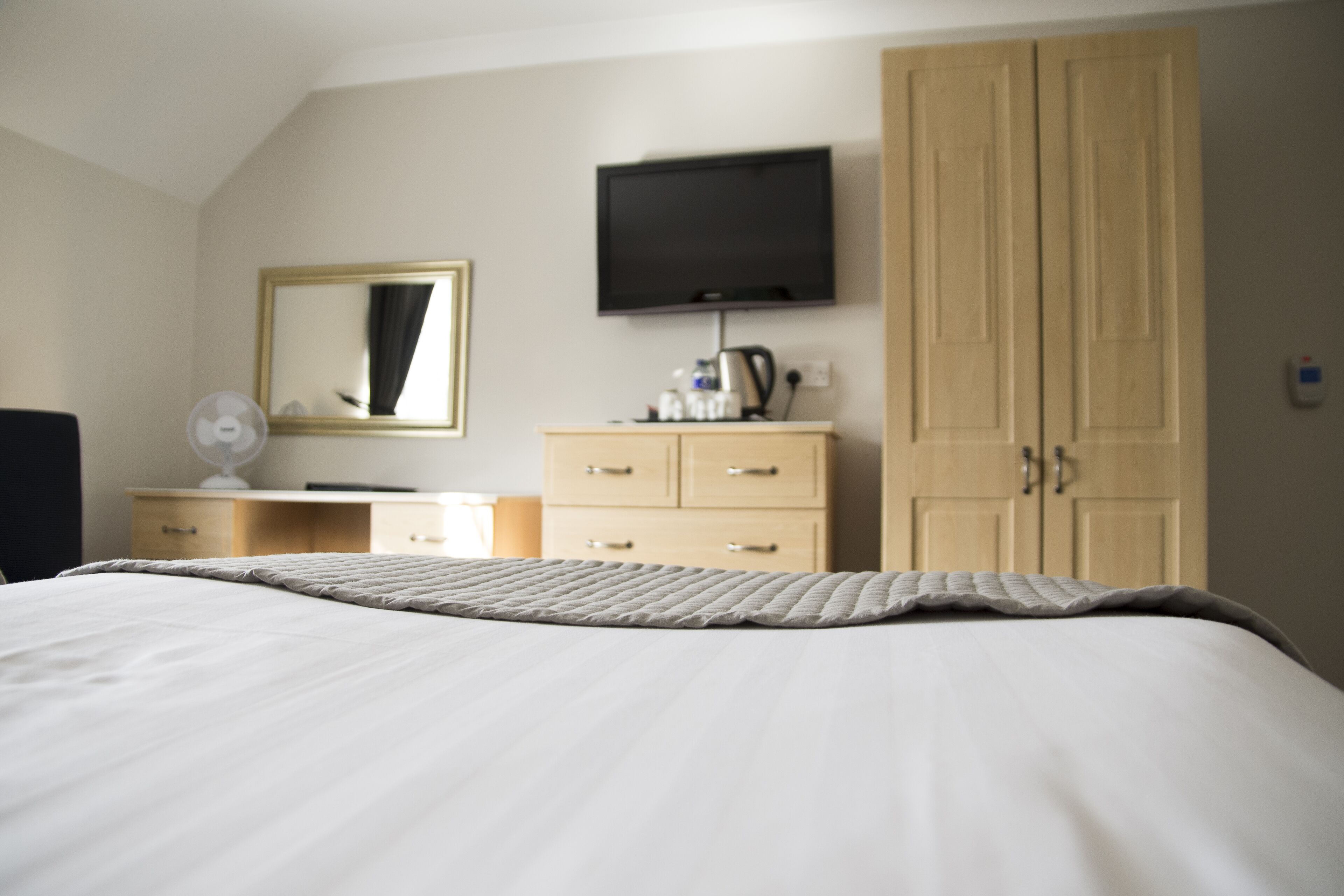 A hotel room with a bed, a dresser, a television, and a wardrobe.