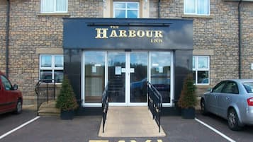 The Harbour Inn with a clear entrance, a sign indicating a taxi drop-off area, and a parking lot with cars.