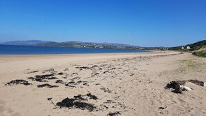 A beach with clear skies, distant hills, and a calm sea. - The Harbour Inn (Buncrana)